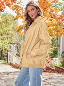 Detail view of a women's oversized tan faux leather motorcycle jacket in autumn setting.