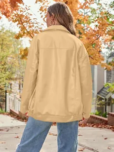 Back view of women's oversized tan faux leather biker jacket in autumn outdoor setting.