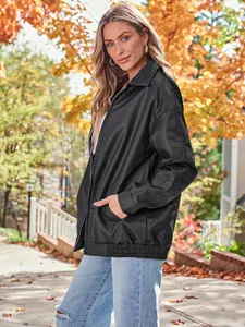 Stylish outdoor shot of a women's oversized black faux leather motorcycle jacket for autumn.