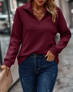 Detail view of a wine red ribbed quarter-zip sweatshirt with loose fit texture