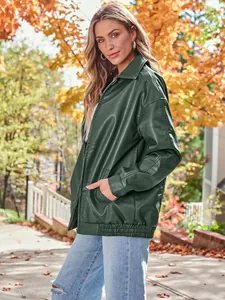 Full view of a dark green oversized leather jacket worn by a model in an autumn setting