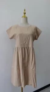 Dettaglio frontale di un abito a trapezio in cotone beige con scollo rotondo.