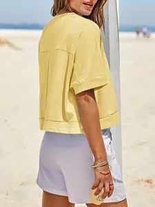 Dettaglio laterale di una t-shirt crop top gialla oversize da donna sulla spiaggia