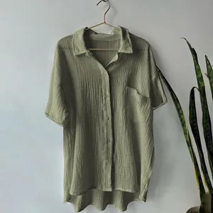 Detailed view of sage green cotton linen shirt with crinkled texture and pocket
