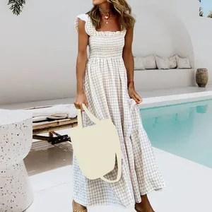 Detail view of a beige gingham maxi dress with smocked bodice and tiered skirt by a pool