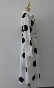 Vista laterale di un abito lungo bianco a maniche lunghe con grandi pois neri.