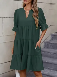 Detalle de un vestido corto escalonado verde bosque con cuello en V y volantes.