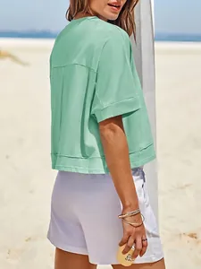 Vista posteriore dettagliata di una maglietta corta oversize verde menta in spiaggia
