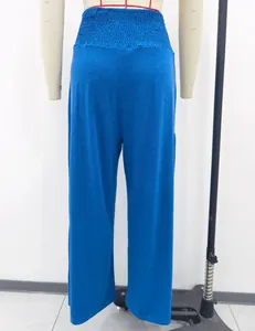 Detail view of blue high-waisted cotton trousers with smocked elastic waistband.