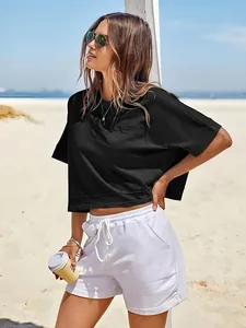 Elegante T-shirt nera corta oversize da donna in una soleggiata ambientazione balneare