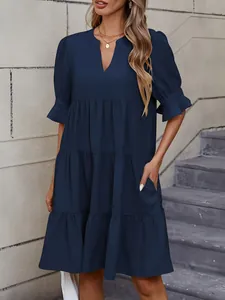 Detalle del vestido azul marino con capas que muestra el escote en V y los volantes