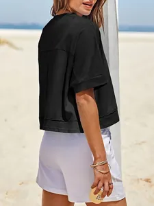 Dettaglio di una t-shirt cropped nera oversize da donna in un ambiente casual in spiaggia.