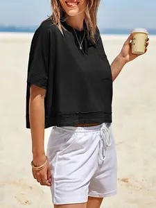Dettaglio della maglietta corta nera oversize con taschino in ambiente spiaggia