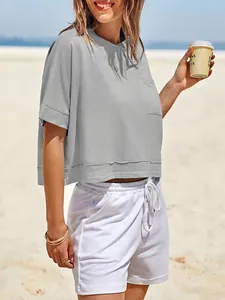 Dettaglio della maglietta grigia crop top oversize con tasca in un ambiente balneare.