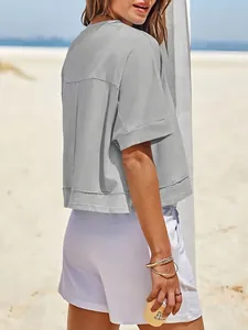 Vista laterale posteriore dettagliata di un crop top grigio oversize sulla spiaggia