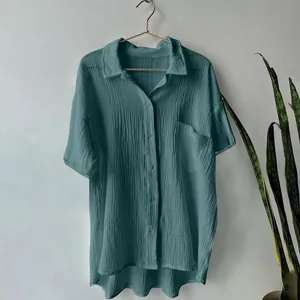 Detail view of a teal cotton linen shirt featuring crinkle texture and a chest pocket