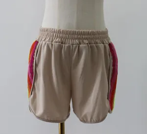 Close-up of beige casual shorts featuring vibrant color-contrast side stripes on mannequin