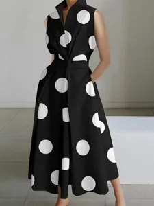 Detail view of sleeveless black dress with large white polka dots and V-neckline