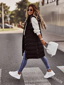 Chic black long hooded puffer vest styled with white sweater and jeans on street.