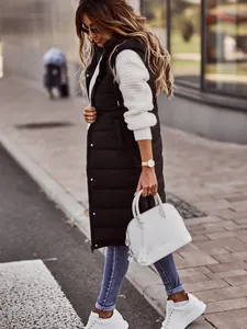 Side view of a long black hooded puffer vest worn by a model in an outdoor urban setting