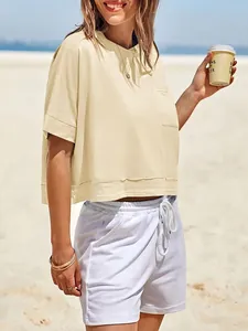 Primo piano di un crop top giallo oversize con pantaloncini estivi bianchi con coulisse.