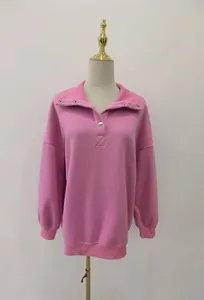 Detail of a pink oversized Henley sweatshirt with button lapel and warm fleece lining.