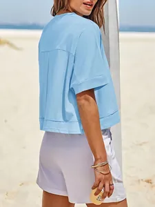 Dettaglio vista posteriore di una t-shirt cropped azzurra oversize indossata in spiaggia