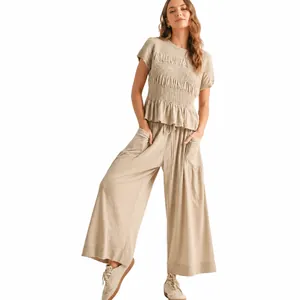 Elegant beige two-piece set featuring smocked short sleeve top and relaxed wide leg pants