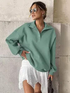 Detail view of a sage green oversized Henley collar sweatshirt on a female model