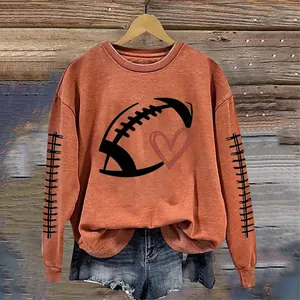 Detail of women's orange rugby print sweatshirt with heart graphic and long sleeves.