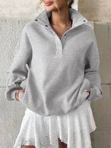 Detailed view of grey oversized long sleeve sweatshirt with buttoned Henley collar.