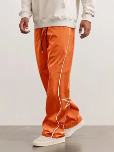 Détail du pantalon streetwear orange pour homme avec un motif d'étoile blanche