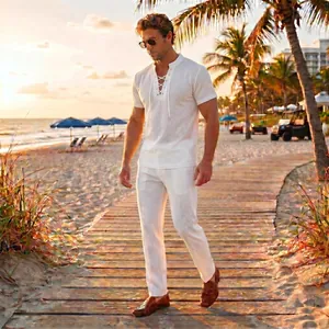 Men's white summer linen-style lace-up shirt and trousers set walking on a sunny beach path