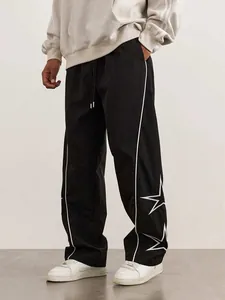 Détail d'un pantalon décontracté noir pour homme avec liseré blanc et broderie d'étoile.