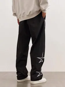 Vue détaillée d'un pantalon noir streetwear avec broderie étoile blanche sur la jambe