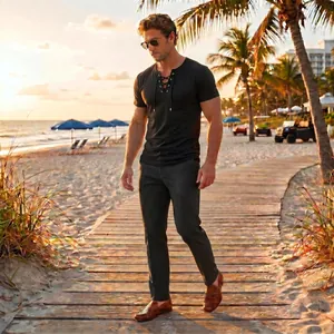 Macro view of men's black lace-up shirt and grey trousers on a tropical beach walk.
