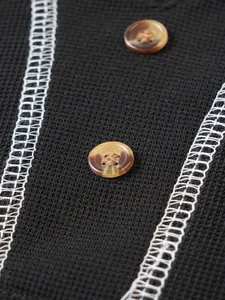 Detailed close-up of black seersucker knit fabric featuring marbled buttons and white stitching.