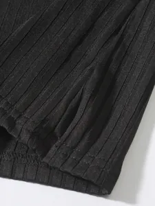 Gros plan de la texture du tissu en maille côtelée noire et des coutures d'un gilet de sport.