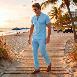 Full view of light blue men's lace-up summer short sleeve and pants set on a beach
