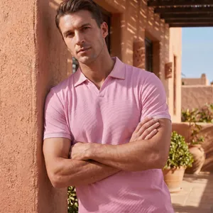Detail eines rosa Kurzarm-Poloshirts am Modell in sonniger Außenarchitektur-Kulisse