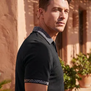 Nahaufnahme eines schwarzen Herren-Poloshirts mit geometrisch gemustertem Kragen