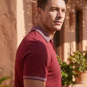 Nahaufnahme eines burgunderfarbenen Poloshirts mit geometrischem Muster an Kragen und Ärmeln