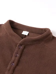 Close-up van de bruine fleece sweatshirtkraag met knopen en een wit maatlabel.