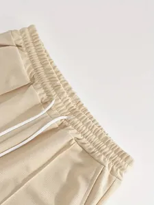 Dettaglio ravvicinato della cintura in maglia waffle beige con coulisse bianca