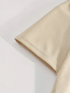 Dettaglio ravvicinato della trama a nido d'ape beige sulla manica di una maglietta sportiva.