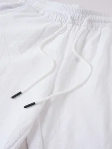 Gros plan sur un pantalon en lin blanc avec taille élastique et cordon à embouts noirs.