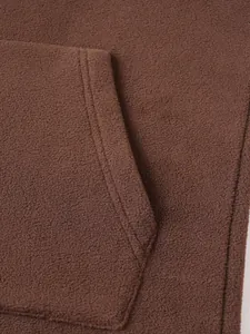 Gedetailleerde macro-opname van bruine fleece stof en zakstiksels op een heren winterhoodie