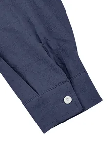 Close-up detail of men's navy blue cotton linen shirt sleeve cuff with a white button