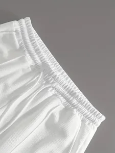 Dettaglio dei pantaloncini sportivi bianchi a nido d'ape con vita elastica e lacci