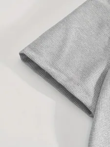 Dettaglio macro del tessuto traspirante grigio a nido d'ape sulla manica del set sportivo